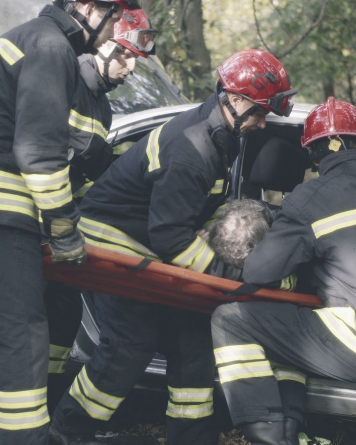 Firefighters lifting an injured driver from a wrecked car